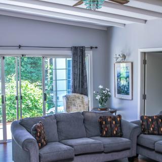 A cozy living room with a grey sofa, large sliding doors, and ample natural light.