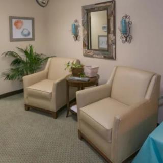 A cozy waiting room with two beige chairs, a small table, and decorative elements.