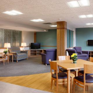 A cozy lounge area with comfortable seating, tables, and a TV.