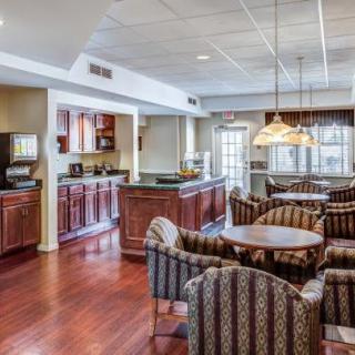 A cozy dining area with a kitchen, featuring wooden floors and comfortable seating.