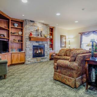 A cozy living room featuring a fireplace, comfortable sofas, and built-in bookshelves.