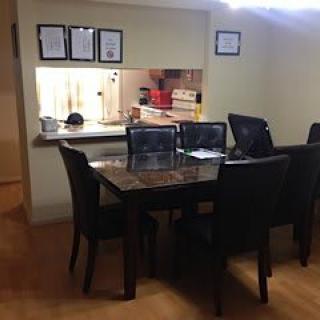A dining area with a polished table and chairs, adjacent to an open kitchen.