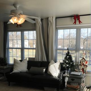 A cozy living room with a sofa, large windows, and festive Christmas decorations.
