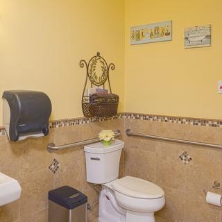 A well-organized bathroom with yellow walls, featuring a toilet, sink, and wall decorations.