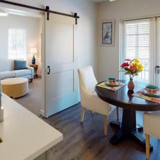 A cozy, modern interior featuring a dining area with a round table set for two, connected to a living room by a sliding barn door.