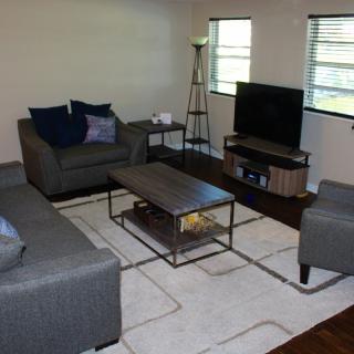 A cozy living room with gray sofas, a coffee table, TV, and modern decor.