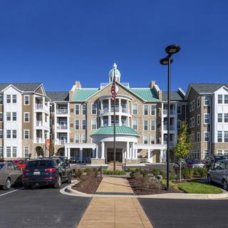 A modern residential apartment building with a well-maintained parking area and landscaping.