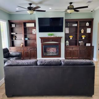 A cozy living room features a sofa facing a fireplace with a mounted television and built-in bookshelves on either side.