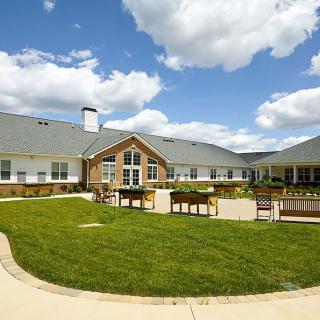 A residential building with a spacious lawn and bright blue sky above.