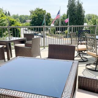 A sunny outdoor patio with modern furniture and a view of flags in the distance.