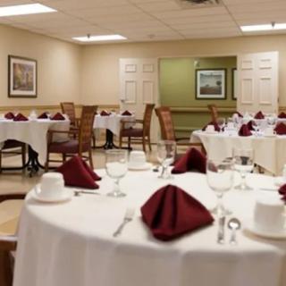A banquet hall with tables set up for a formal dining event, featuring white tablecloths and red folded napkins.