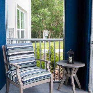 A cozy patio corner featuring a striped chair and small table with a lantern.