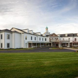 A large white building with a well-maintained lawn under a partly cloudy sky.