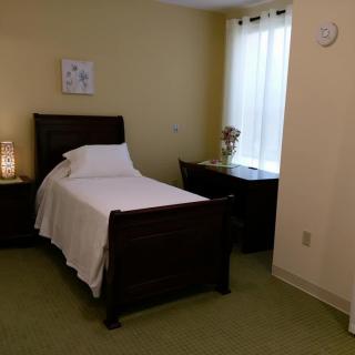 A cozy bedroom with a single bed, nightstand, and window.