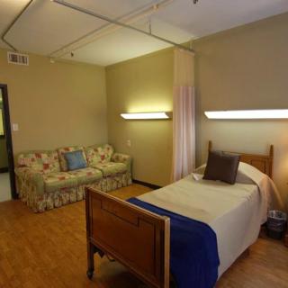 A cozy bedroom with a single bed and sofa, featuring soft lighting.