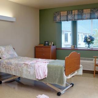 A hospital room with a single bed, a window, and basic furnishings.