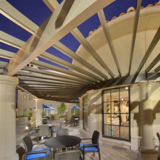 A modern outdoor seating area with a pergola and patio furniture, captured in the evening.