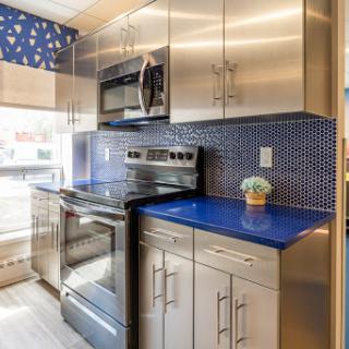 A sleek and modern kitchen featuring stainless steel appliances, a vibrant blue countertop, and an eye-catching decorative backsplash.