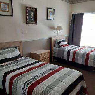 A neatly arranged bedroom with twin beds featuring striped bedding and wall decor.