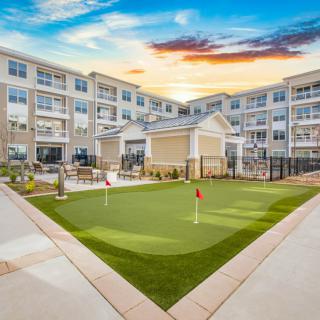 A modern apartment complex featuring a landscaped courtyard with a putting green.