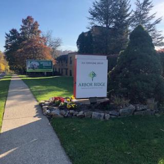 A welcoming sign surrounded by vibrant landscaping on a sunny autumn day.