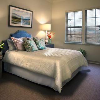 A cozy bedroom with a neatly made bed, decorative pillows, and soft lighting.