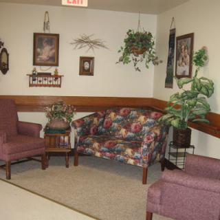 A cozy waiting area featuring floral patterned seating and decorative plants.