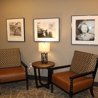 A cozy corner with two armchairs, a small round table, and framed pictures on the wall.