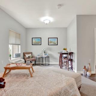 A modern and cozy bedroom with soft lighting, featuring a neatly made bed, comfortable seating, and decorative paintings on the wall.