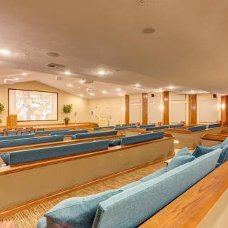 Interior of a church with wooden pews and a large screen.