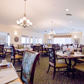 An elegantly designed dining room with neatly arranged tables and chairs, illuminated by chandeliers.