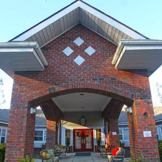 A brick building with a prominent entrance and a peaked roof, captured during the day.