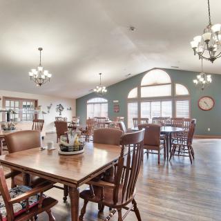 A spacious dining room featuring wooden furniture, large windows, and elegant chandeliers.