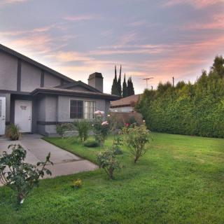 A beautiful yard with a well-maintained lawn and garden, showcasing a house at sunset.