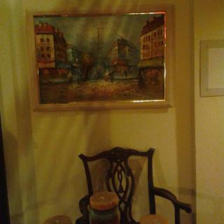 A room interior featuring a framed painting above an ornate chair.