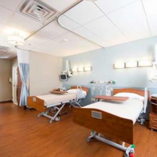 A hospital room with two medical beds and various healthcare equipment.