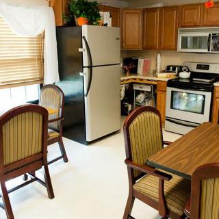 A cozy kitchen with wooden cabinets, a refrigerator, and a dining table with chairs.