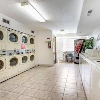 A clean and spacious laundromat featuring rows of washing machines, dryers, and a vending machine.