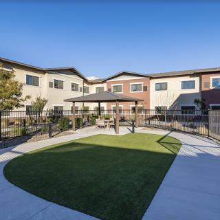 A modern residential building with a fenced courtyard featuring a grassy area.