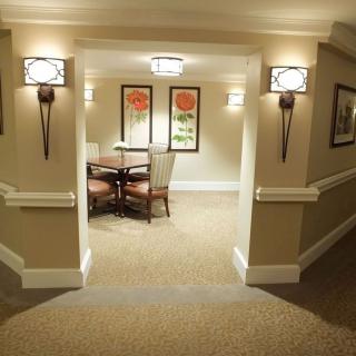 A well-lit hallway with seating area and floral artwork on the walls.