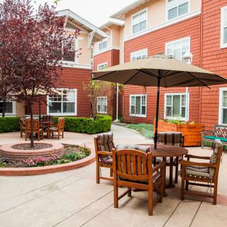A cozy courtyard with outdoor seating and umbrellas in an apartment complex.