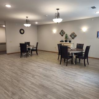 A spacious modern dining area with tables and chairs, featuring wooden flooring and stylish lighting.