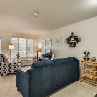 A cozy living room with a blue sofa, patterned armchair, and decorative artwork on the walls.