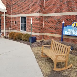 An outdoor view of a residential building featuring a wooden bench and a sign.
