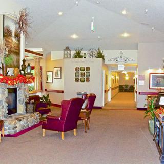 A cozy lobby with a fireplace and comfortable seating areas, adorned with plants and artwork.