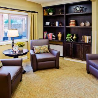 Cozy living room with armchairs, a bookshelf, and a window with natural light.