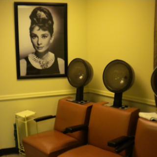 A vintage-style salon interior with hairdryers and a classic poster on the wall.