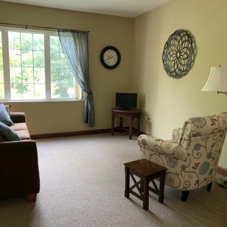 A cozy living room with a sofa, armchair, and a small television by the window.