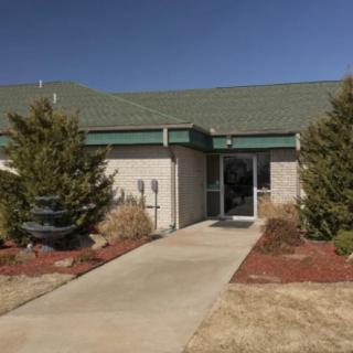 A small building entrance with a paved sidewalk and landscaping.