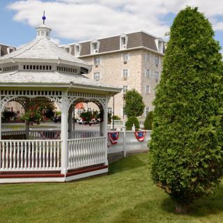 A scenic gazebo in a park setting with a large building in the background.